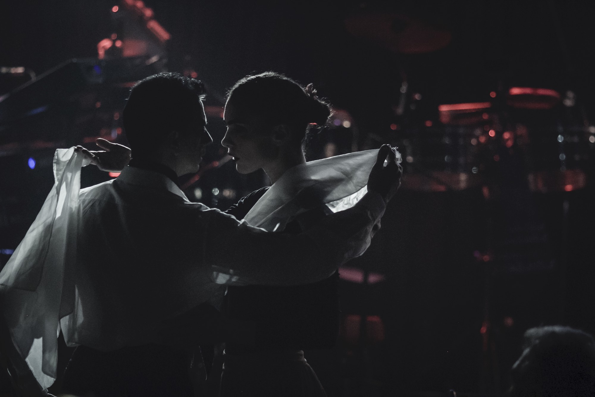Ο Ariel Perez και η Margarita Plessa χορεύουν zamba στο σκοτάδι κρατώντας μαντίλια στα χέρια τους.